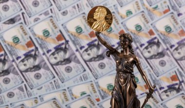 Themis 'in rakamı ve Nobel ödüllü madalya 100 dolarlık banknotların arka planına karşı.