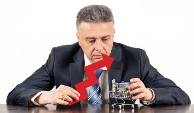 Kırmızı büyüme grafikli orta yaşlı bir adam ve süpermarket alışveriş arabasında 100 dolarlık banknot.