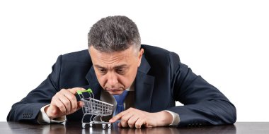 Takım elbiseli orta yaşlı bir adam ve boş süpermarket alışveriş arabası.