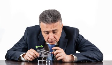 Takım elbiseli orta yaşlı bir adam ve boş süpermarket alışveriş arabası.