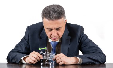 Takım elbiseli orta yaşlı bir adam ve boş süpermarket alışveriş arabası.