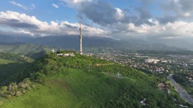 Kok Tobe Dağı (Mavi Tepe) ve ünlü TV kulesi Kazak şehri Almaty 'deki Zailiyskiy Alatau dağ sırasının arka planına karşı bir bahar akşamı