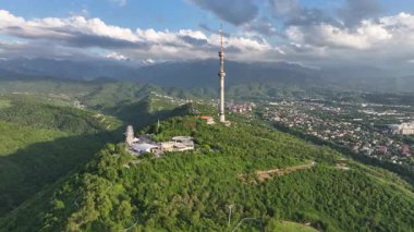 Kok Tobe Dağı (Mavi Tepe) ve ünlü TV kulesi Kazak şehri Almaty 'deki Zailiyskiy Alatau dağ sırasının arka planına karşı bir bahar akşamı