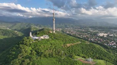 Kok Tobe Dağı (Mavi Tepe) ve ünlü TV kulesi Kazak şehri Almaty 'deki Zailiyskiy Alatau dağ sırasının arka planına karşı bir bahar akşamı