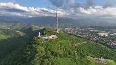 Kok Tobe Dağı (Mavi Tepe) ve ünlü TV kulesi Kazak şehri Almaty 'deki Zailiyskiy Alatau dağ sırasının arka planına karşı bir bahar akşamı