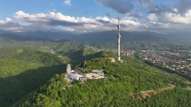 Kok Tobe Dağı (Mavi Tepe) ve ünlü TV kulesi Kazak şehri Almaty 'deki Zailiyskiy Alatau dağ sırasının arka planına karşı bir bahar akşamı