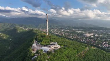 Kok Tobe Dağı (Mavi Tepe) ve ünlü TV kulesi Kazak şehri Almaty 'deki Zailiyskiy Alatau dağ sırasının arka planına karşı bir bahar akşamı