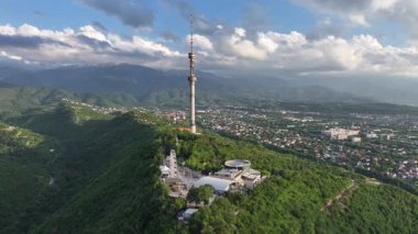Kok Tobe Dağı (Mavi Tepe) ve ünlü TV kulesi Kazak şehri Almaty 'deki Zailiyskiy Alatau dağ sırasının arka planına karşı bir bahar akşamı