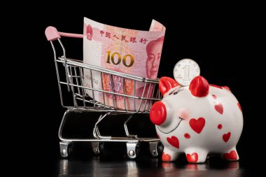 1 Çin Yuan sikkesi, domuz kumbarası ve 100 Yuan banknot ve siyah arka planda Başkan Mao portresi.