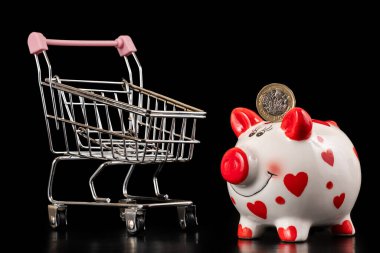 İçinde 1 İngiliz poundu ve boş bir süpermarket arabası olan bir kumbara.