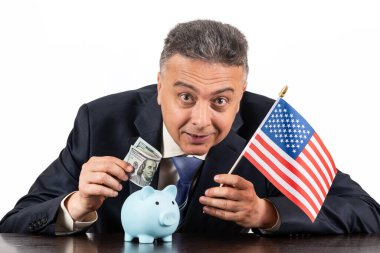 Amerikan bayrağı, kumbarası ve 100 dolarlık banknotu olan orta yaşlı bir adam.