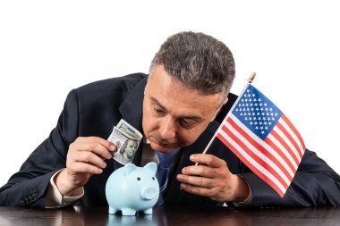 Amerikan bayrağı, kumbarası ve 100 dolarlık banknotu olan orta yaşlı bir adam.