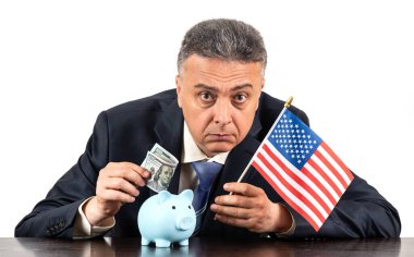 Amerikan bayrağı, kumbarası ve 100 dolarlık banknotu olan orta yaşlı bir adam.