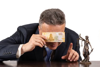 Takım elbiseli orta yaşlı bir adam, 100 ruble banknot ve Themis figürü.