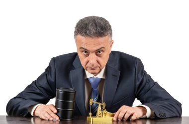 Orta yaşlı iş adamı, petrol ürünleri için demir fıçı ve beyaz arka planda minyatür altın yağ pompası.