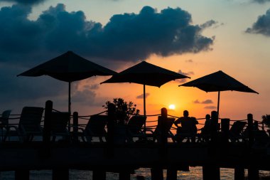 Türkiye 'nin Antalya ilinde bir yaz sabahı güneşin doğuşuna karşı rıhtımdaki şemsiyeler