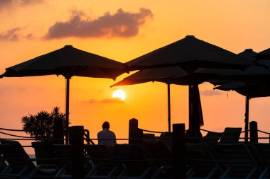 Türkiye 'nin Antalya ilinde bir yaz sabahı güneşin doğuşuna karşı rıhtımdaki şemsiyeler