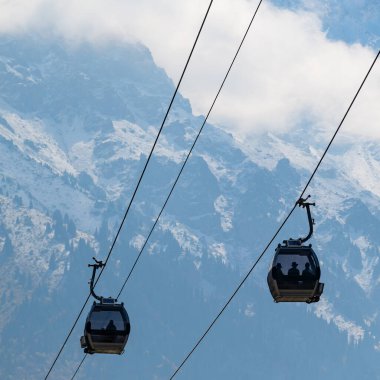 Bulutlu bir sonbahar gününde, bir dağ sırasının arka planına karşı bir teleferik.