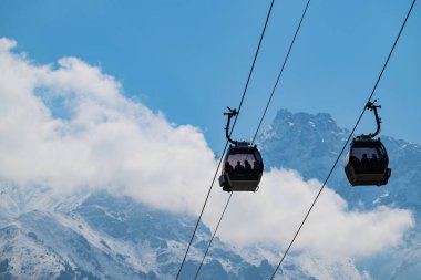 Bulutlu bir sonbahar gününde, bir dağ sırasının arka planına karşı bir teleferik.