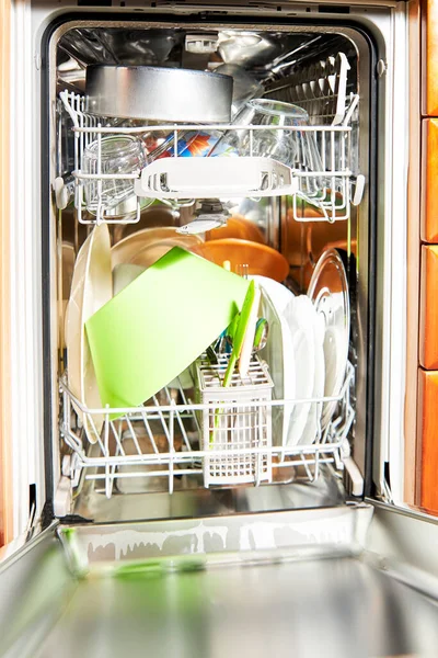 Open dishwasher with clean dishes at home kitchen. Bowls and utensils in the dishwasher