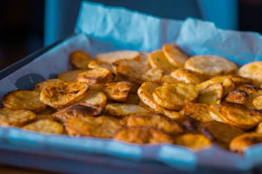 Tepside duran dilimlenmiş patates cipsi ya da dolar cipsi. Fırından yeni çıkmış patates parçaları..