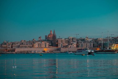 Valletta, Malta şehrinin altın saatinde ya da mavi saatte bir sonbahar akşamında. Şehirde durgun su ve ışık olan güzel bir manzara..