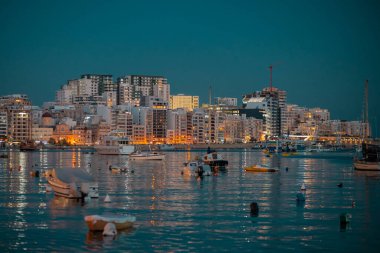 Sliema, Malta 'da deniz kenarındaki Tal.Karmnu adlı kilise günbatımından hemen önce sonbahar güneşinin tadını çıkarıyor. Körfeze bak.
