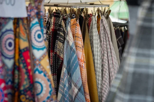 Açık pazarda farklı kumaş ve renkte eşarp asılı. Markette satılan eşarplar gibi pek çok giysi..