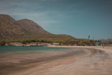 Cabo Verde adalarındaki Santiago adasındaki Pucturesque sahilinde, arka planda bazı ağaçlar ve evler var..