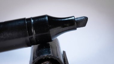 Keçe uçlu kalemin siyah renkli ayrıntılı veya makro fotoğrafı bir başlık ve beyaz arkaplanda dinleniyor.