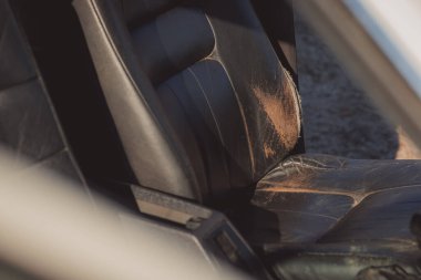 Old and worn leather seat in a car. Seat just waiting to be freshly upholstered with a new patch of leather. Poor condition of a drivers seat.