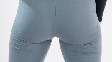 Detail or closeup view of butt or buttocks in gray yoga pants. Tight fit of stretch fabric on behind.