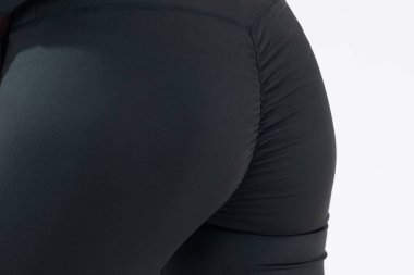 Detail or closeup view of butt or buttocks in black yoga pants. Tight fit of stretch fabric on behind.