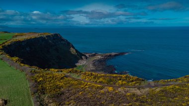 Kuzey İrlanda 'daki Giants geçidinde kayalıklardan, altıgen taşlardan ya da sütunlardan oluşan drone panorama bulutlu bir günde sahilde görkemli bazalt sütunlar. Alanın geniş görünümü..