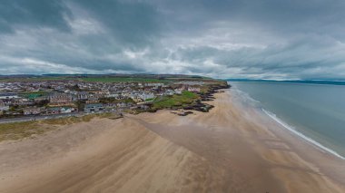 Castlerock, Kuzey İrlanda 'da, bulutlu bir bahar gününde kumlu kumsalın hava aracı manzarası. Kara bulutlar, rüzgar ve alçak gelgit Castlerock sahil kasabasında.