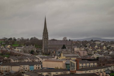 Derry ya da Londonderry Panoraması şehir duvarlarından görülen bulutlu bir günde. Şehrin yeşil manzarası, kilise ya da katedral görünür..