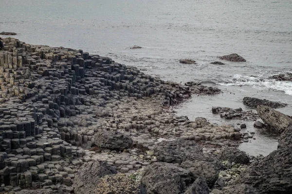 자이언트 둑길에 육각형의 돌이나 기둥들 구름낀 해변에 현무암 기둥들을 갖추고 — 스톡 사진