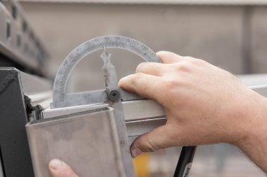 Açı ölçer ile alüminyum profilleri ölçülüyor. 90 dereceden biraz daha az görünüyor..