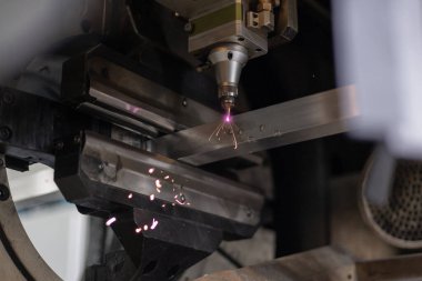 Alüminyum bir profilde delik açarken lazer plazma kesici kullanılıyor. Çelik, alüminyum ve diğer malzemeleri lazerle kesmek için büyük modern bir makine. Hortum ve kıvılcımların ayrıntıları.