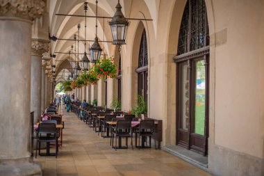 Krakow Meydanı 'ndaki atari salonlarını ya da yaz günlerinde Glavny Rynek' i görmek. Çatıdan sarkan görünür sandalyeler ve çiçekler.