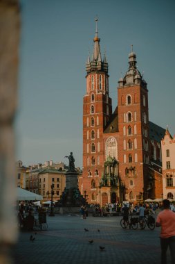 Polonya 'nın Krakow kentindeki Saint Mary Bazilikası' nın manzarası güneşli bir yaz gününde şehir meydanındaki atari salonlarından izleniyor..