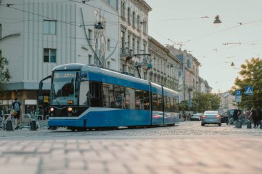 Polonya 'nın Krakow kentindeki mavi halk tramvayı. Yaz akşamının başlarında, işlek şehrin sokaklarında at sürerken. Polonya şehrinde modern tramvay.