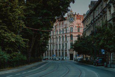 Krakow 'un eski kasabasındaki pek çok klasik evden biri ya da yakında, güneşin batışıyla aydınlatılan. Aşağıdaki yol ve tramvay rayları görünür..