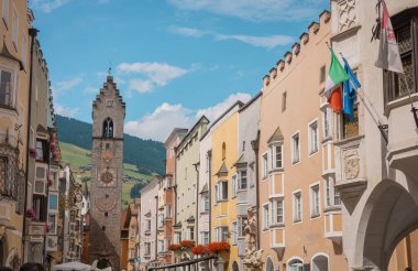 Vipitieno şehir merkezinin çan kulesi, bazı çiçeklerin arkasında ve güzel mavi bir gökyüzünün önünde saklanıyor. Kare taştan yapılmış kule.