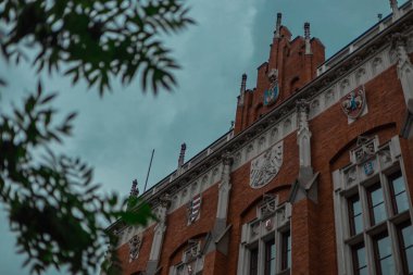 Krakow 'daki Jagielonski Üniversitesi, şehir merkezindeki tuğla ev manzaralı bir yaz günü. Görülebilir ağaçlar ve kırmızı tuğla ev.
