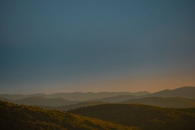 Yaz mevsiminde, Slovenya 'nın Dolenjska bölgesinde akşam yağmurundan hemen sonra tepelerin manzarası. Derin, mavi gökyüzü ve aşağıdaki sarı ormanlar.