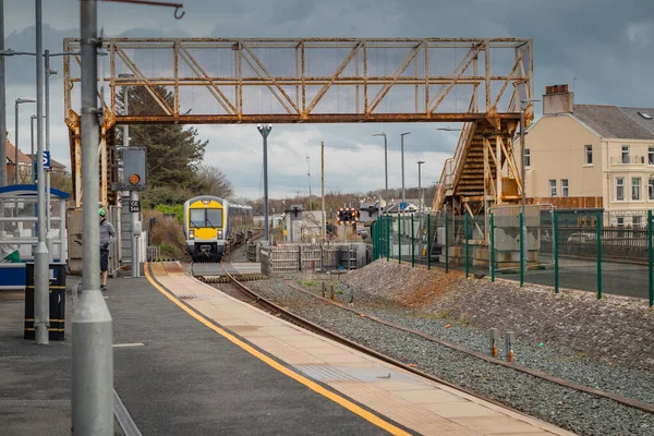 Dizel tren bulutlu bir günde Castlerock Tren İstasyonu 'na geliyor. Castlerock 'ta küçük bir durakla Derry' ye doğru giden bir patika var. Görünür yaya üstgeçidi.