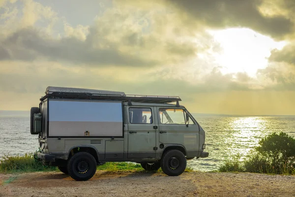 Adventure camper van or campmobile parked next to a nice beach at sunrise on a picturesque island of Losinj. Road trip with an old van.
