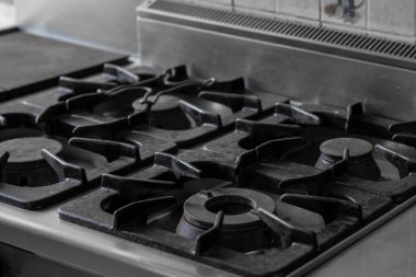 Demir gaz deposu dök, üzerinde ızgara olan bir soba parçası detayı ve görünen gaz için başlık. Gri, soğuk bir yemek tepesi resmi.