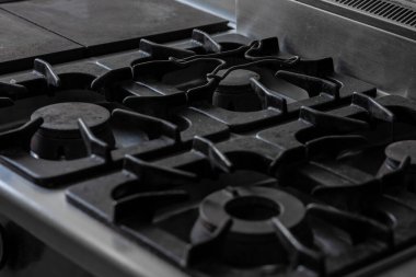 Demir gaz deposu dök, üzerinde ızgara olan bir soba parçası detayı ve görünen gaz için başlık. Gri, soğuk bir yemek tepesi resmi.